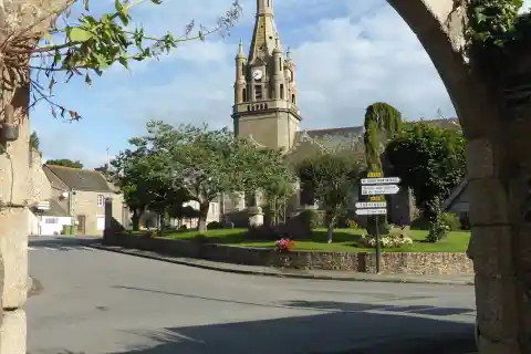 L'église Saint-Pierre de Plourhan, dans les Côtes-d'Armor, vue à travers une arche près de la mairie
